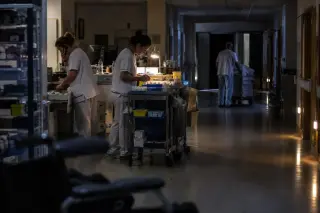 La nuit dans un service hospitalier : une infirmière prépare un chariot de soins, un aide-soignant pousse du linge